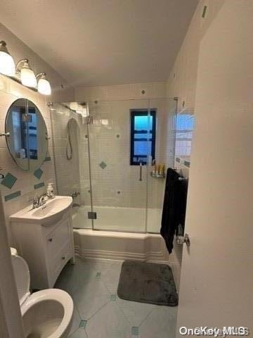 full bathroom with vanity, toilet, and combined bath / shower with glass door