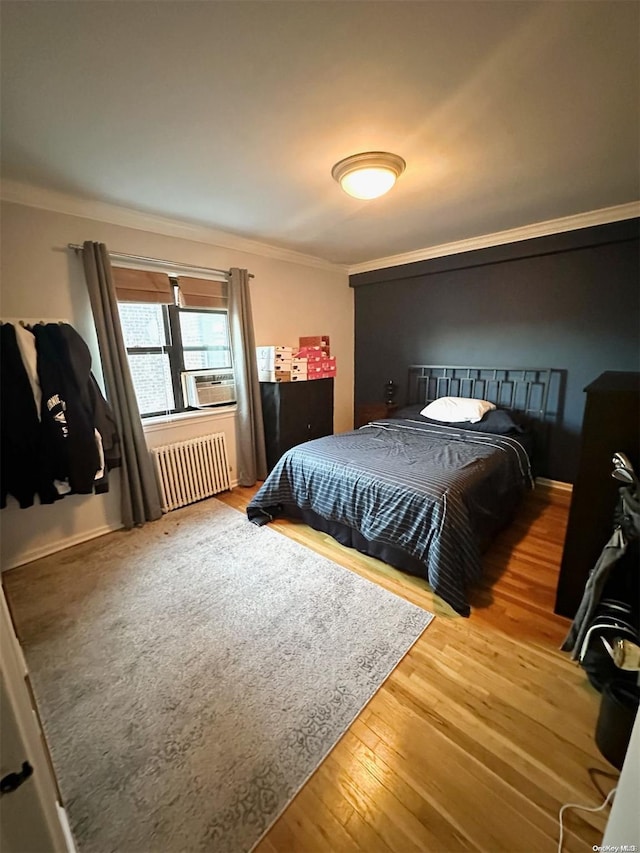 bedroom featuring hardwood / wood-style floors, crown molding, and radiator