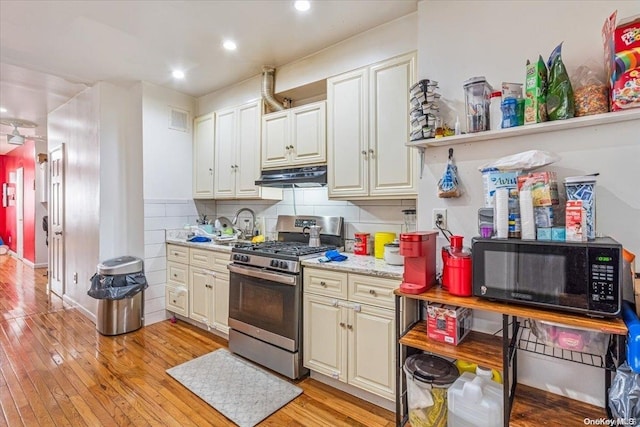 kitchen with gas stove, light hardwood / wood-style floors, and backsplash