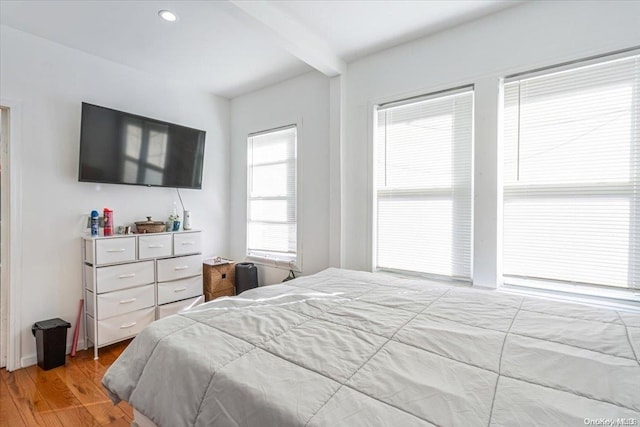 bedroom featuring beamed ceiling and wood-type flooring