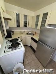 kitchen featuring tile patterned flooring, white appliances, and sink