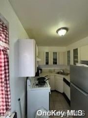 kitchen featuring white cabinetry, sink, white range oven, kitchen peninsula, and fridge