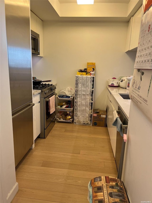 138-35 39th Ave Unit 10F, Flushing, NY 11354 - kitchen with stainless steel appliances, white cabinetry, light countertops, and light wood-style flooring