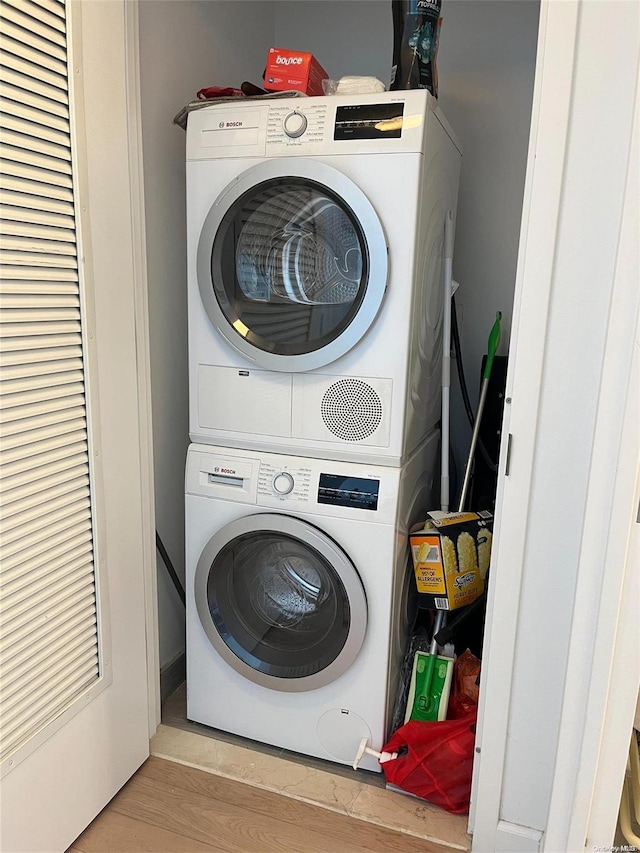 laundry area with stacked washer and dryer and light hardwood / wood-style flooring