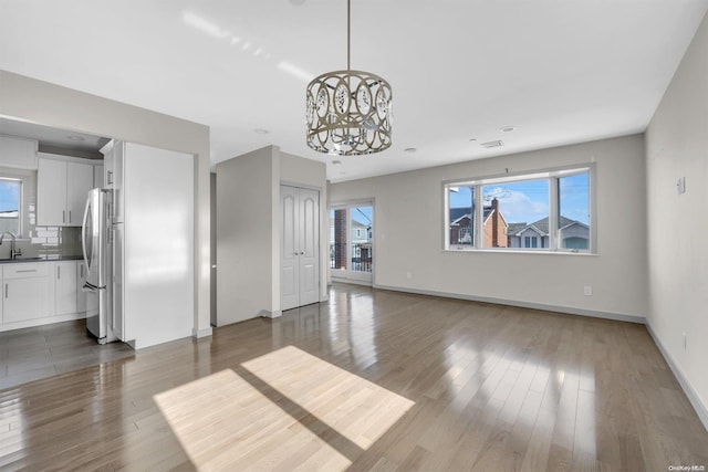 unfurnished living room featuring sink, dark wood-type flooring, and a notable chandelier