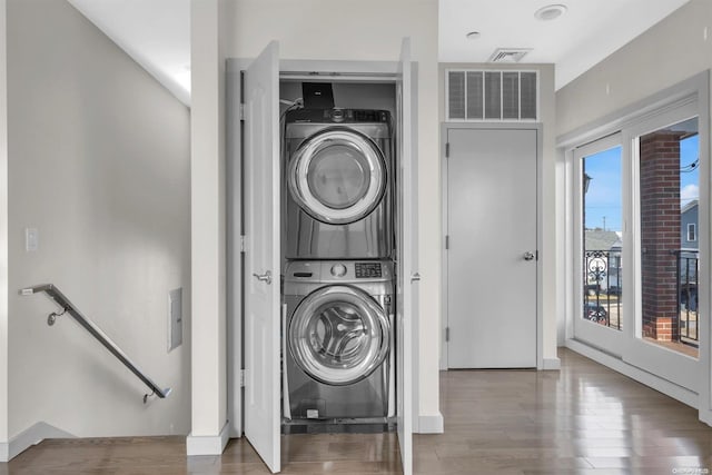 laundry room with hardwood / wood-style floors and stacked washer and dryer