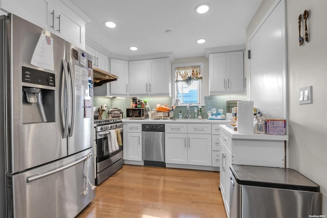 kitchen with sink, tasteful backsplash, appliances with stainless steel finishes, white cabinets, and light wood-type flooring