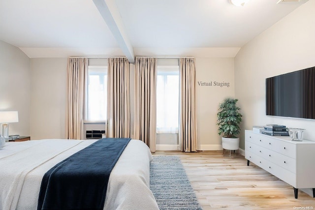 bedroom with beam ceiling, light hardwood / wood-style floors, and multiple windows