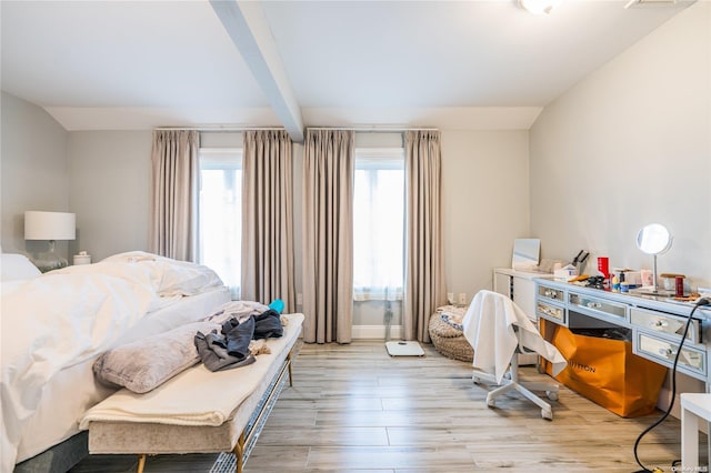 bedroom with beamed ceiling, light hardwood / wood-style floors, and multiple windows