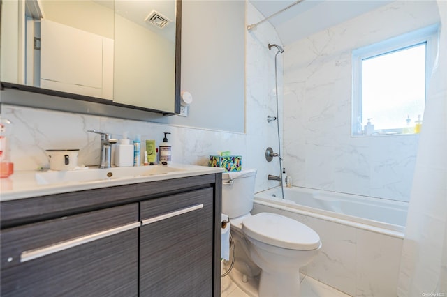 full bathroom with vanity, tiled shower / bath combo, toilet, and tile walls