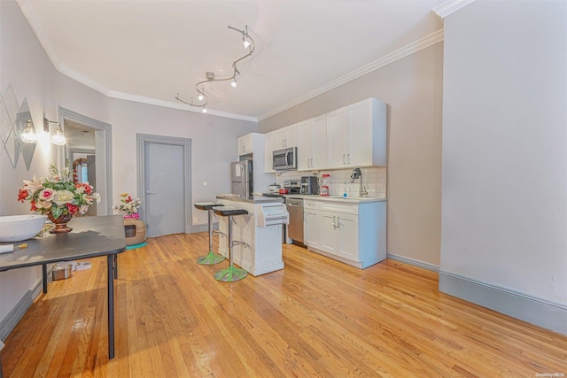 kitchen featuring white cabinets, a kitchen breakfast bar, sink, light hardwood / wood-style flooring, and appliances with stainless steel finishes