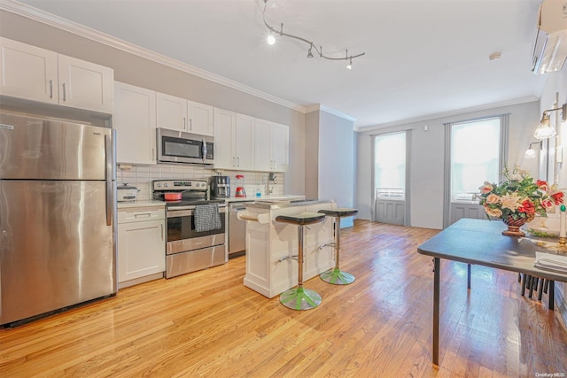 kitchen with white cabinets, light wood-type flooring, stainless steel appliances, and a breakfast bar