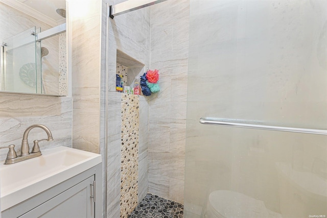 bathroom with vanity, a shower with door, toilet, tile walls, and tasteful backsplash