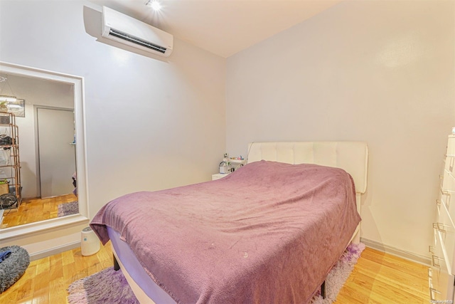 bedroom featuring light wood-type flooring and a wall unit AC