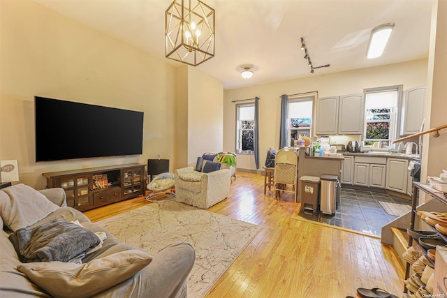 living room featuring light hardwood / wood-style floors, track lighting, and an inviting chandelier