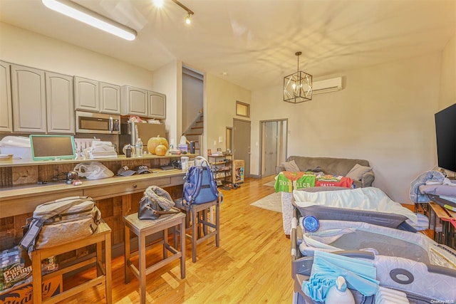 interior space featuring stainless steel appliances, a wall unit AC, a chandelier, decorative light fixtures, and light hardwood / wood-style floors