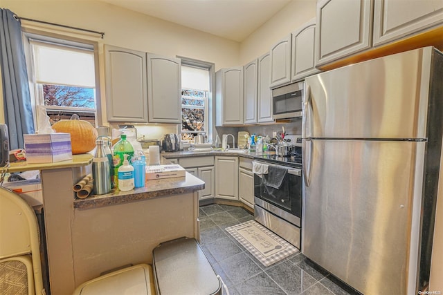 kitchen featuring appliances with stainless steel finishes, dark tile patterned floors, and sink