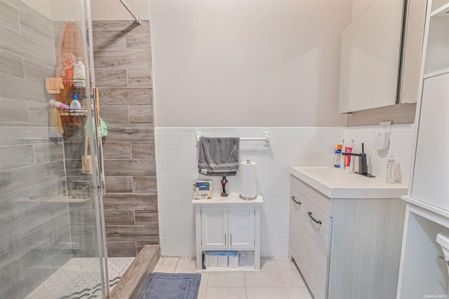 bathroom featuring tile patterned floors, vanity, a shower with shower door, and tile walls