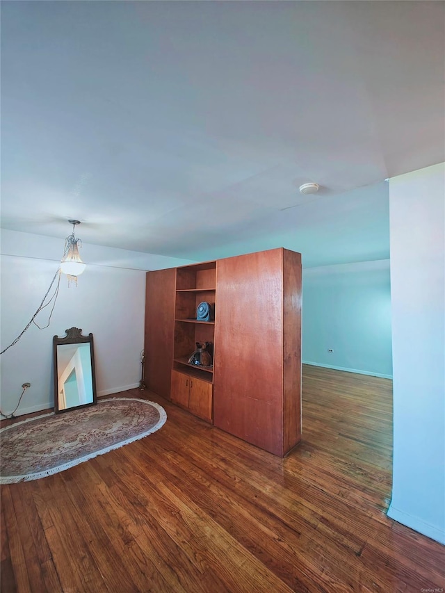 unfurnished living room with built in shelves and dark wood-type flooring