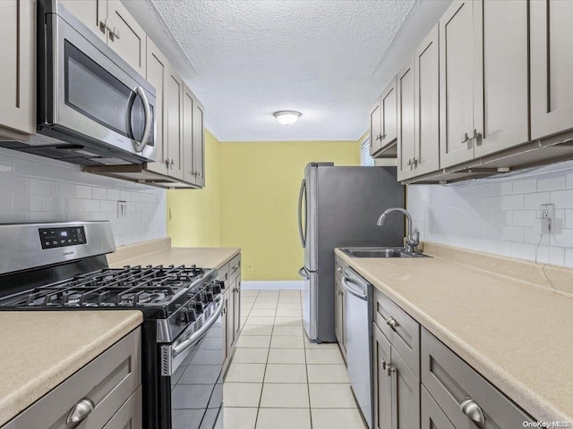 kitchen featuring appliances with stainless steel finishes, backsplash, gray cabinets, and light tile patterned flooring