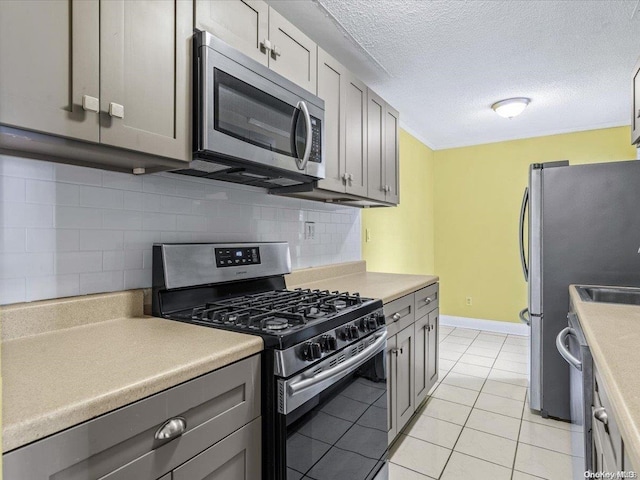 kitchen with gray cabinets, backsplash, and appliances with stainless steel finishes