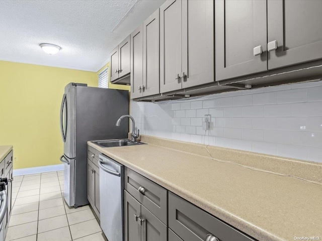 kitchen featuring gray cabinetry, decorative backsplash, sink, and stainless steel dishwasher