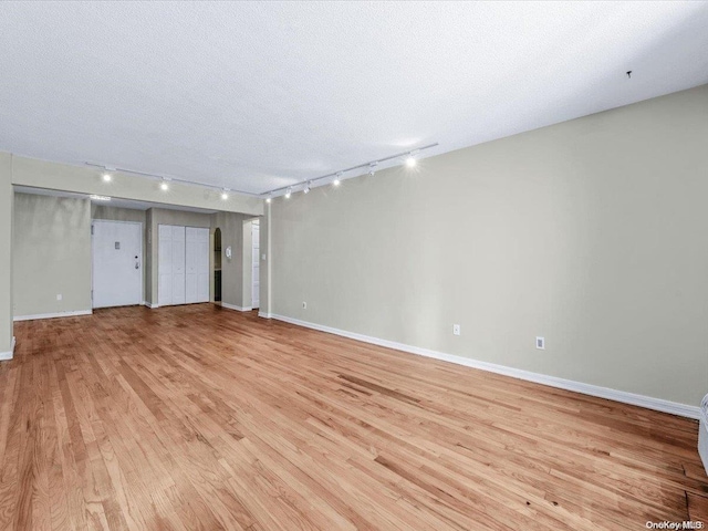 interior space featuring a textured ceiling, rail lighting, and light hardwood / wood-style flooring