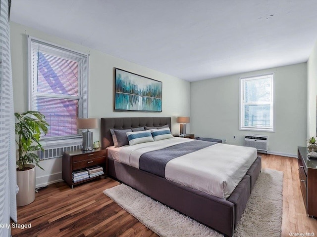 bedroom featuring dark hardwood / wood-style floors and an AC wall unit