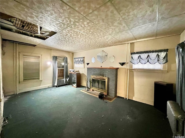 unfurnished living room featuring concrete flooring, a fireplace, and radiator