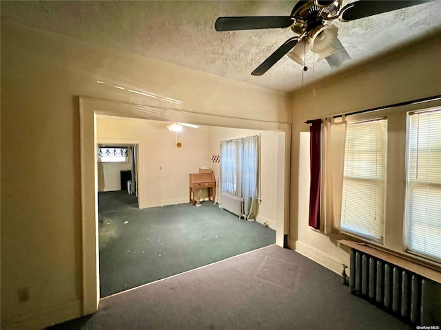 carpeted empty room with ceiling fan, radiator heating unit, and a textured ceiling