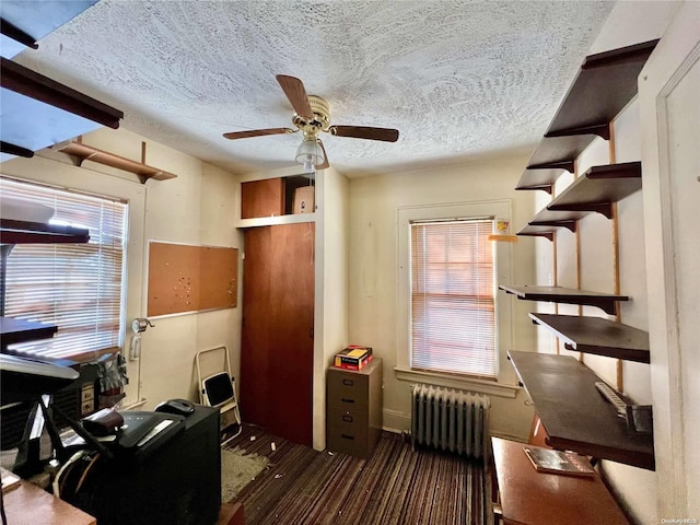 home office featuring dark hardwood / wood-style flooring, a textured ceiling, radiator, and ceiling fan