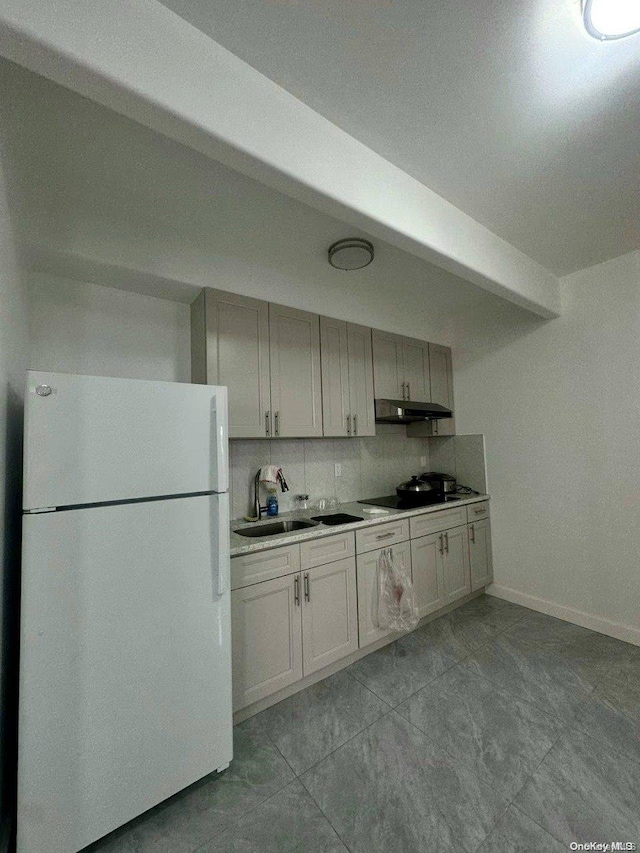 kitchen featuring tasteful backsplash, sink, white fridge, and black stovetop