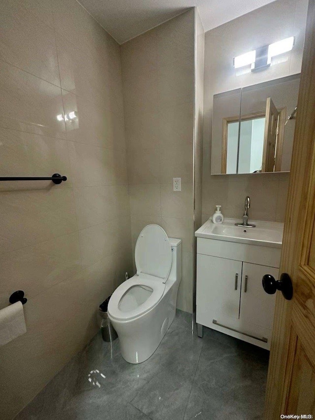 bathroom featuring vanity, toilet, and tile walls