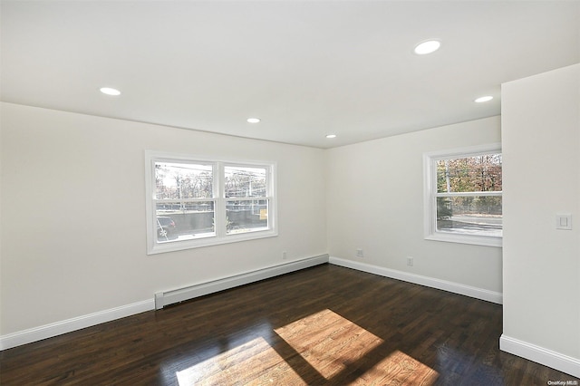 empty room featuring dark wood-type flooring and a baseboard heating unit