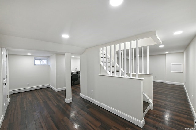 basement with dark hardwood / wood-style flooring, baseboard heating, and washer / clothes dryer