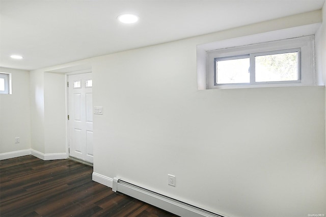 unfurnished room with a healthy amount of sunlight, dark wood-type flooring, and a baseboard radiator