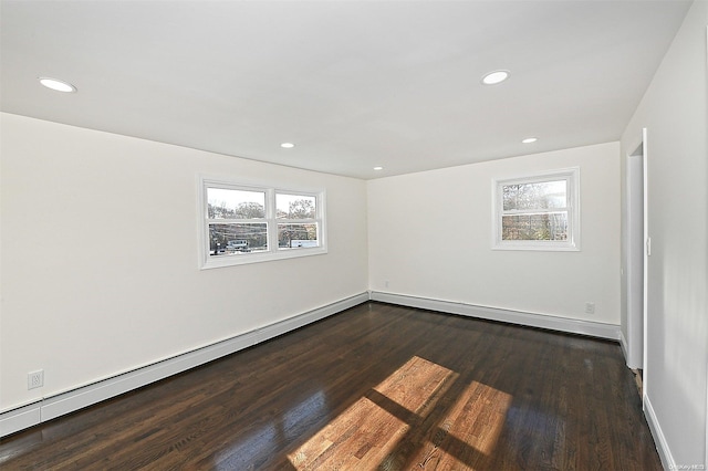 spare room with dark hardwood / wood-style flooring, a healthy amount of sunlight, and a baseboard radiator