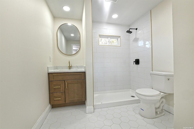 bathroom featuring tiled shower, vanity, tile patterned flooring, and toilet