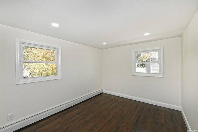 spare room featuring a healthy amount of sunlight, baseboard heating, and dark wood-type flooring