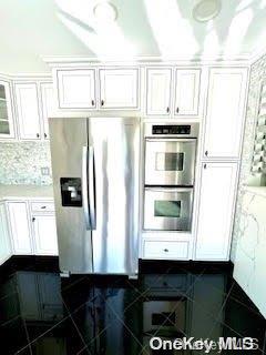 kitchen with white cabinets, appliances with stainless steel finishes, and backsplash