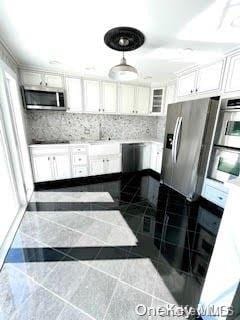 kitchen with tasteful backsplash, white cabinetry, and stainless steel appliances