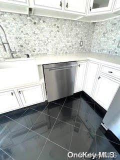 kitchen featuring white cabinets, dishwasher, and dark tile patterned flooring