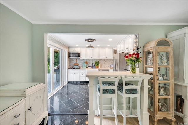 kitchen with a kitchen breakfast bar, stainless steel appliances, pendant lighting, dark hardwood / wood-style floors, and white cabinetry