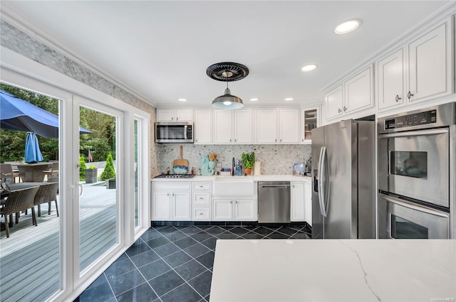 kitchen featuring light stone countertops, stainless steel appliances, decorative light fixtures, white cabinets, and ornamental molding