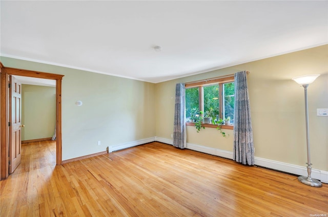 spare room featuring light hardwood / wood-style floors, a baseboard radiator, and crown molding