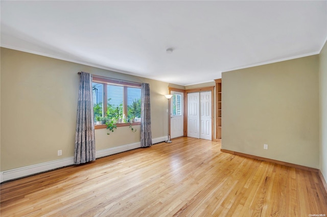 spare room with light hardwood / wood-style flooring, baseboard heating, and crown molding