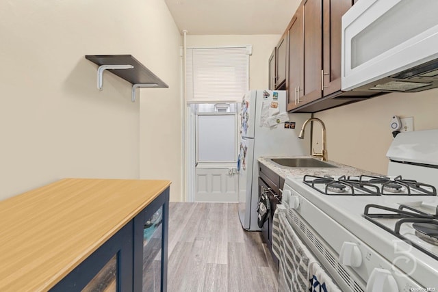 kitchen with light hardwood / wood-style floors, white appliances, and sink