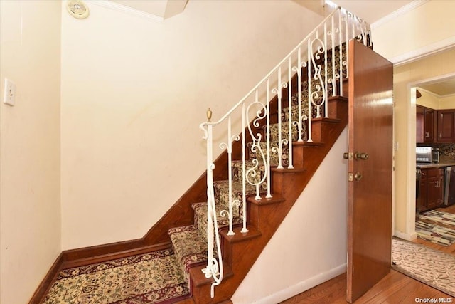 stairs with hardwood / wood-style flooring and ornamental molding