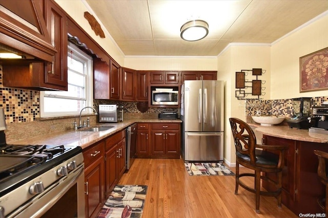 kitchen featuring sink, stainless steel appliances, tasteful backsplash, and light hardwood / wood-style flooring