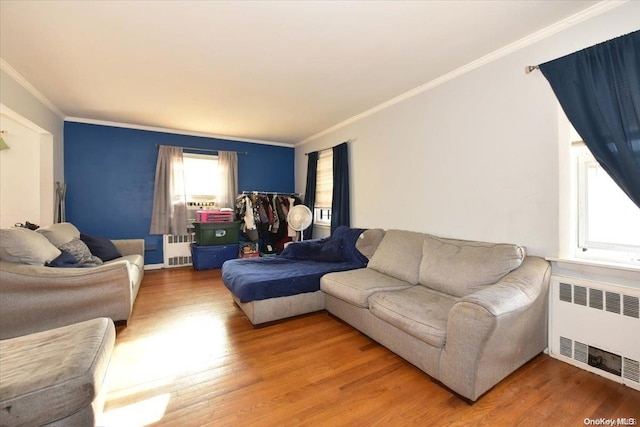 living room featuring hardwood / wood-style flooring, crown molding, and radiator